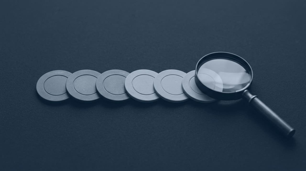 A magnifying glass resting beside a row of plain unmarked tokens.