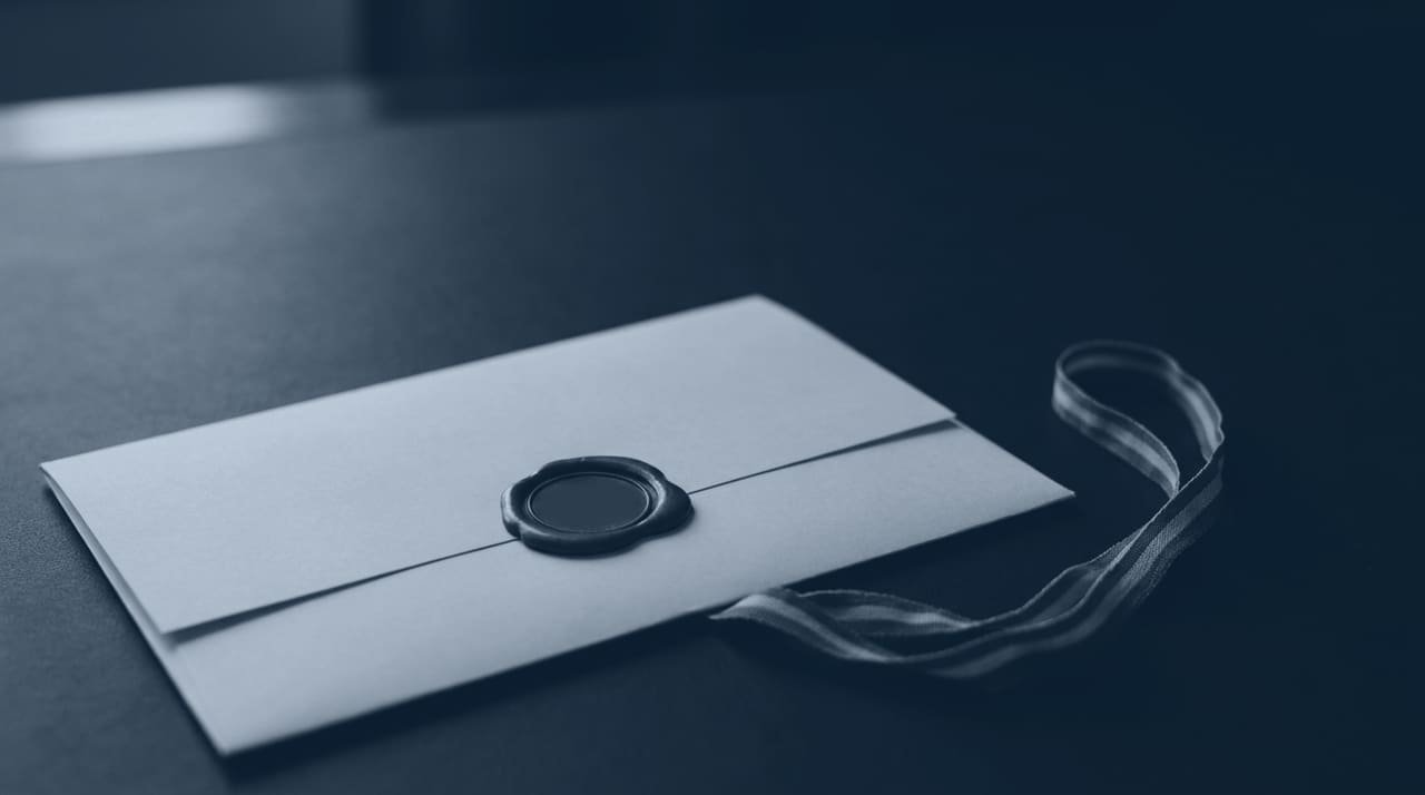A sealed document folder and a plain ribbon on a dark desk.